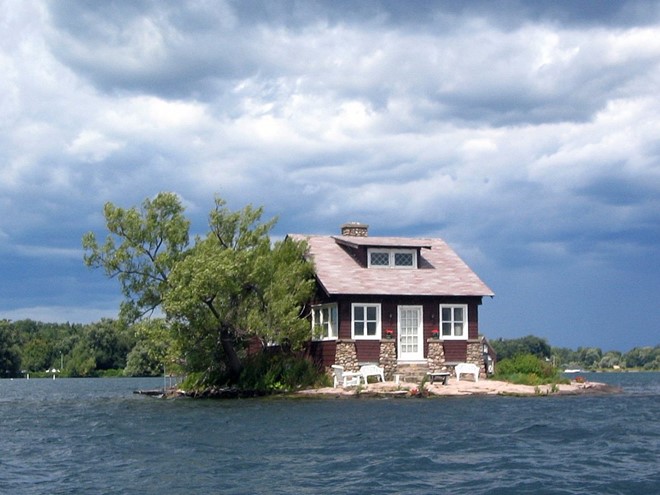 Một ngôi nhà tương tự được xây trên một mỏm đá giữa dòng sông Saint Lawrence, biên giới giữa Mỹ và Canada. Bộ bàn ghế nhỏ được đặt trước hiên nhà. Ảnh: 