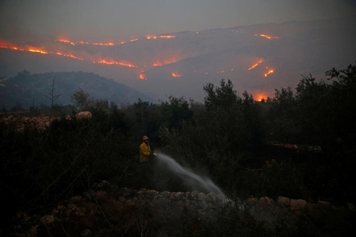 Lính cứu hỏa đang phun nước dập tắt đám cháy quanh một ngôi nhà ở Nataf, ngoại ô Jerusalem
