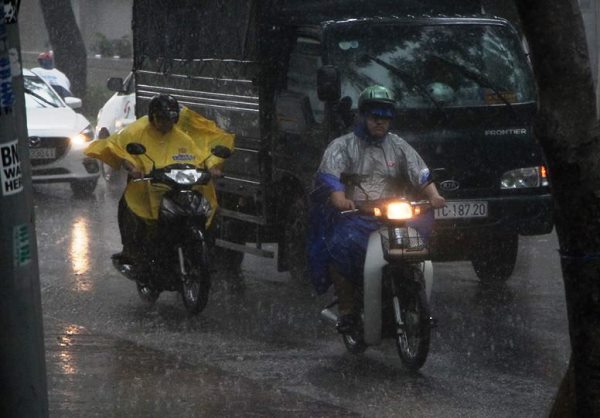 Mưa như trút nước giữa trung tâm Sài Gòn. Dù mới 2h chiều nhưng xe máy, ô tô phải bật đèn để di chuyển