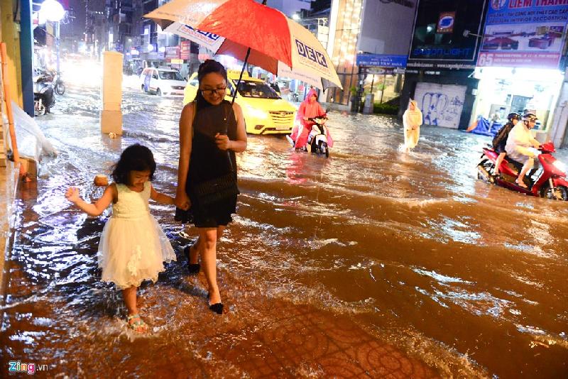 Chị Cẩm Tiên dắt cháu đi nép vào lề đường sau cơn mưa chiều trên đường Phan Đình Phùng, quận Phú Nhuận.