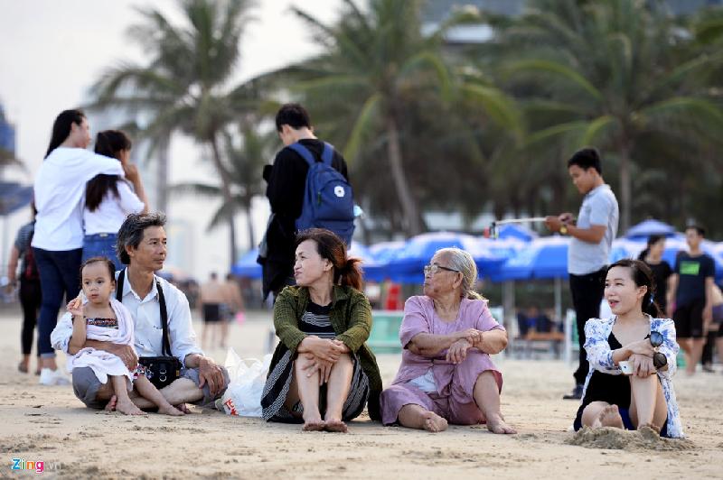 Một gia đình sinh sống tại Đà Nẵng cũng nghỉ ngơi ngoài bãi biển chiều 30/4. Chị Bảo Châu (ngoài cùng bên phải) cho biết cả nhà rất hay ra đây hóng mát và không có nhu cầu bơi hay tắm.