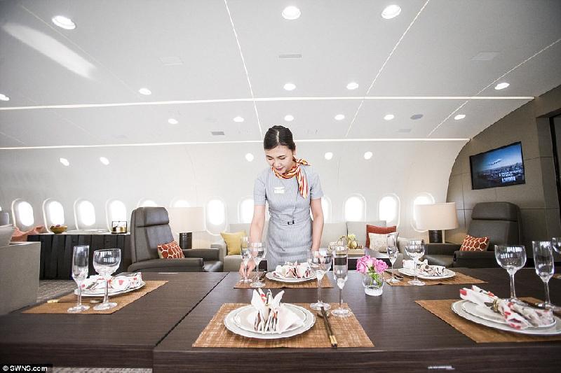 Một tiếp viên hàng không bày bàn gỗ với đồ sứ hạng sang để chuẩn bị cho bữa ăn.