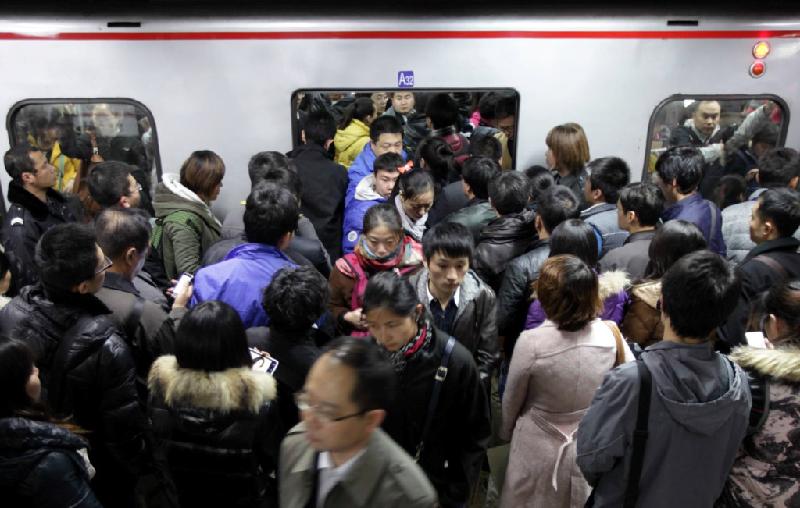Những người đi làm rời khỏi tàu, trong khi đám đông khác đợi lên tàu tại một ga tàu điện ngầm ở Bắc Kinh (Trung Quốc).