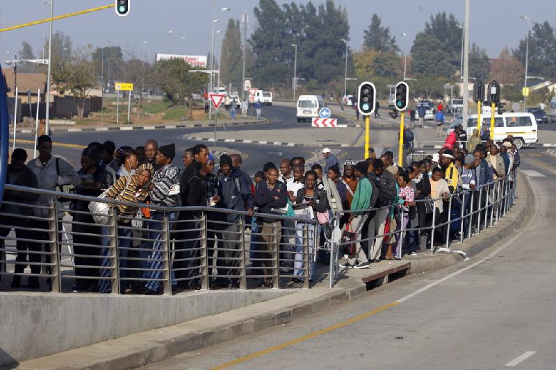 Người đi làm Nam Phi chờ hàng dài tại điểm dừng xe bus ở Soweto.