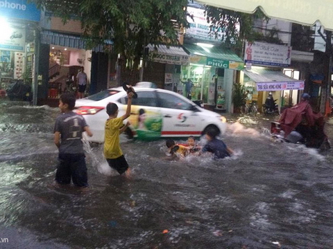 Sài Gòn ngập trong mưa lớn, trẻ nhỏ nô đùa dưới nước
