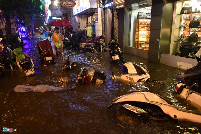 Lượng mưa ngập hơn 100 mm ở khu vực Hoàn Kiếm làm nước dâng lên vỉa hè. Mỗi khi ôtô chạy qua, sóng nước lại làm đổ xe máy dựng trước cửa hàng quán. Ảnh: Tiến Tuấn.