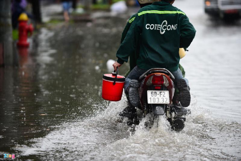 Để tránh bị ướt, công nhân co chân di chuyển qua đường ngập trên đường Điện Biên Phủ.