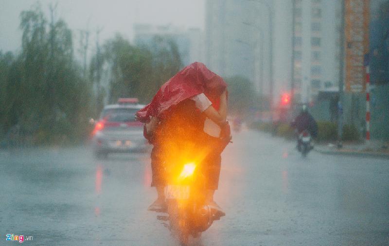 Một đôi bạn trẻ dùng chung áo mưa trên phố Mạc Thái Tổ.