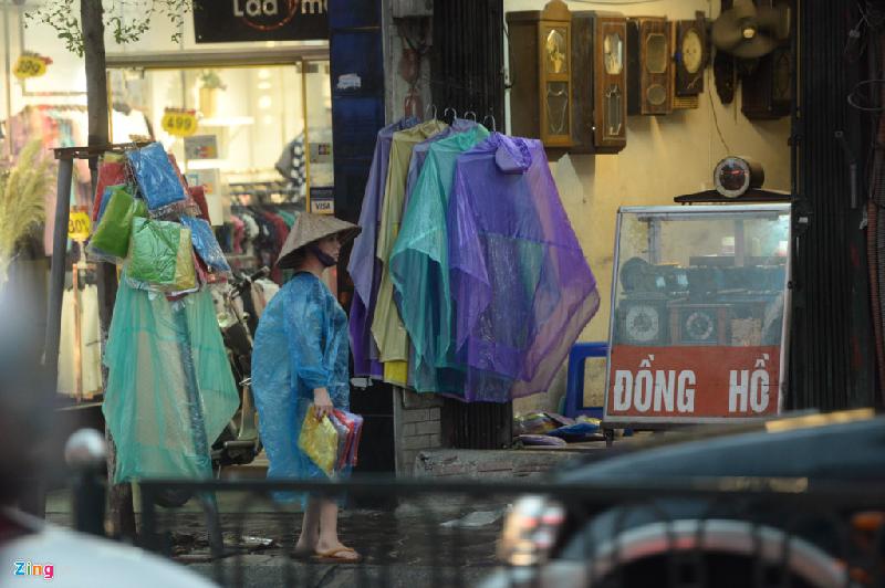 Dọc các tuyến phố, dịch vụ bán áo mưa nhanh chóng xuất hiện. Chủ hàng cầm sẵn áo mưa đứng lề đường đón khách.