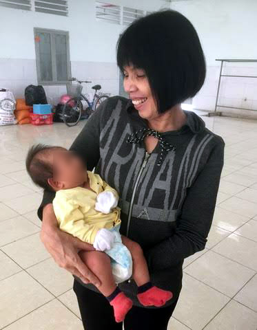Chị Căn, người phụ trách nhà tạm lánh, bế một em bé. Mẹ bé người Ninh Bình vào tạm lánh sau khi chồng bỏ đi vì bệnh ung thư.