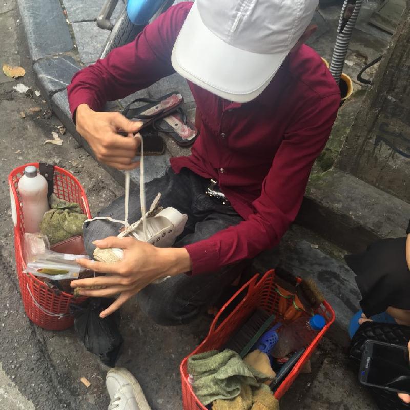 Anh Hà đang ngồi sửa giày cho khách trên phố cổ Hà Nội. Ảnh: Nhật Linh