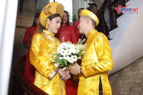Hai vợ chồng cùng diện áo dài vàng với họa tiết tinh xảo, cầu kỳ.